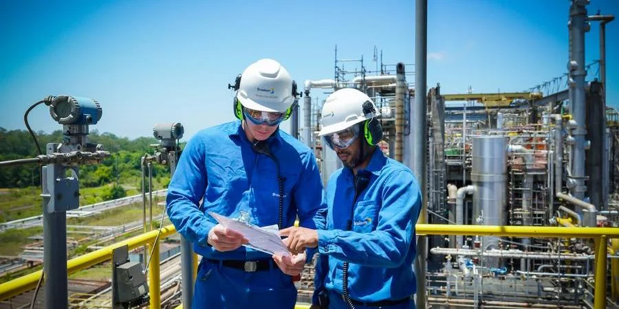 Homens trabalhadores da indústria do plástico, eles vestem macacão azul e capacetes brancos de proteção