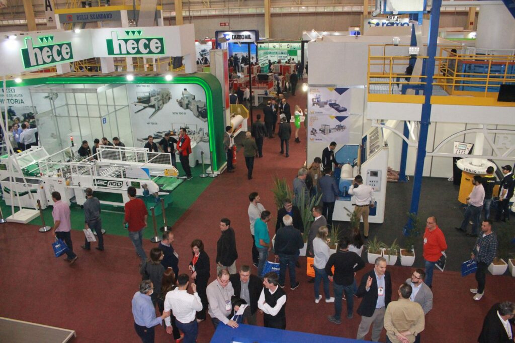 Na imagem aparece a Feira Interplast. Na foto aparecem pessoas se movimentando entre os stands de exposição