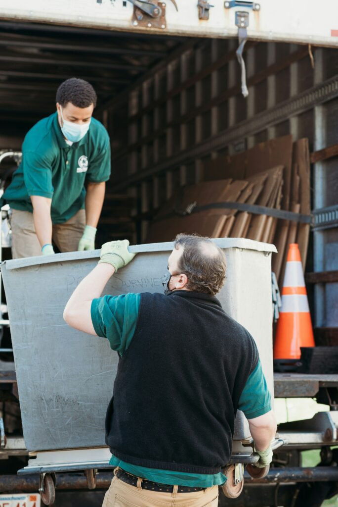 Na imagem aparecem dois homens fazendo o trabalho de coleta para reciclagem